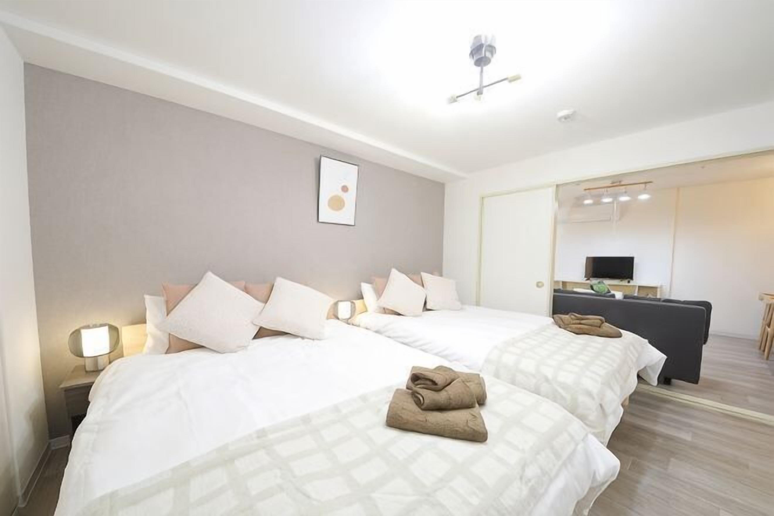Una habitación de hotel con dos camas, un escritorio, una silla y un espejo.