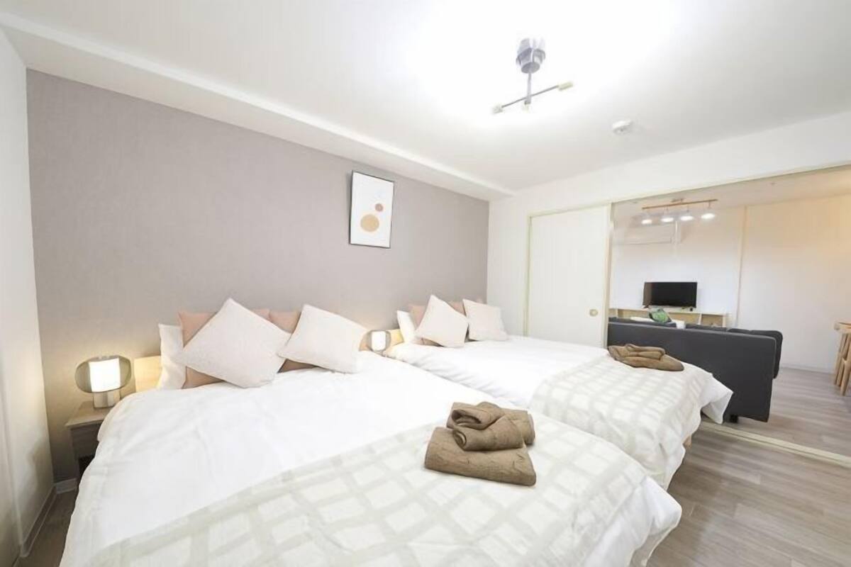 A hotel room with two beds, a desk, a chair, and a mirror.