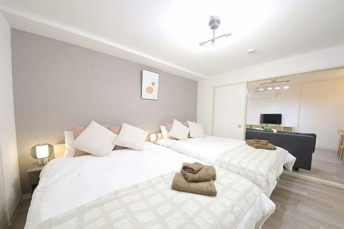 Una habitación de hotel con dos camas, un escritorio, una silla y un espejo.