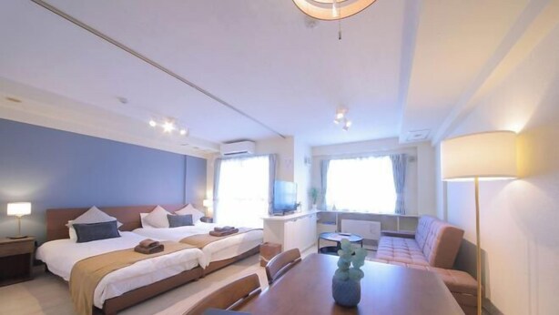 A hotel room with two beds, a dining table, a sofa, a TV, and a window. - Northern Hills Minami 6 (Sapporo)