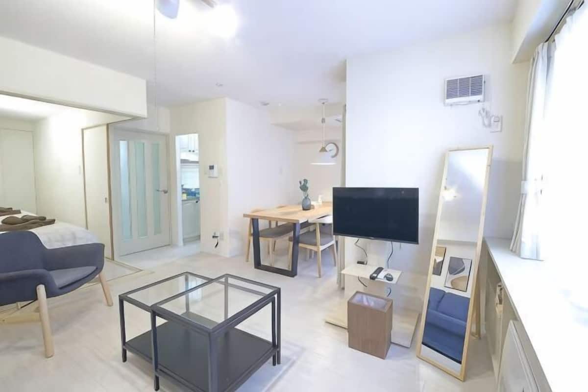 Una sala de estar moderna con una mesa de centro de vidrio, un sofá, un televisor y un comedor.