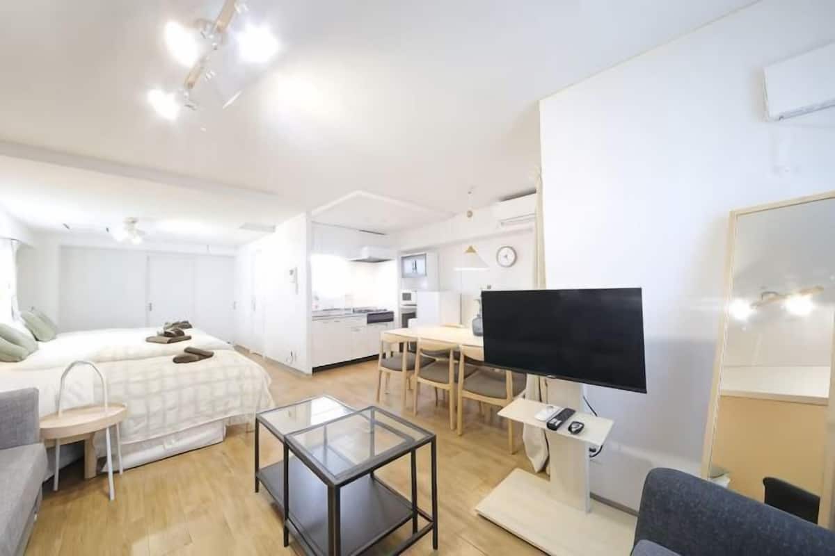 Una habitación moderna y luminosa con una cama, un escritorio, un televisor y un espejo.