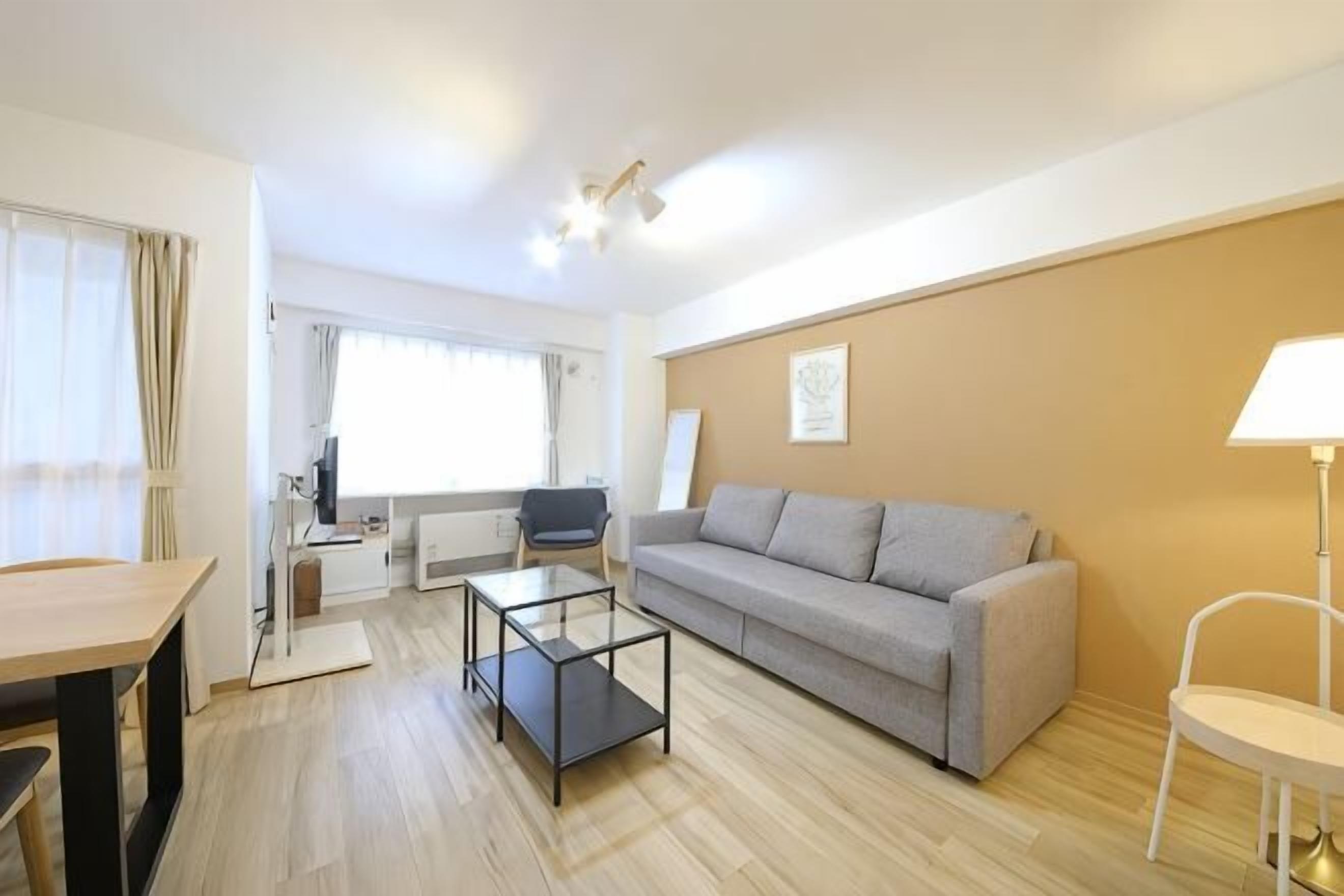 Una sala de estar moderna con un sofá, una mesa de centro, una mesa de comedor y una lámpara.