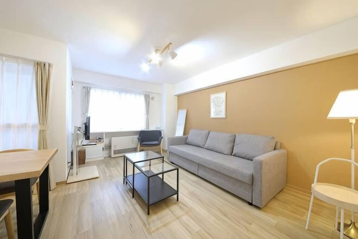 A modern living room with a sofa, a coffee table, a dining table, and a lamp.