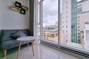 Una sala de estar moderna con un sofá gris, una mesita redonda y un ventanal con vistas a la ciudad.