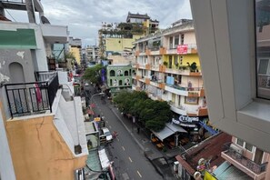 Vista de una calle con edificios de varios pisos, balcones y una diversidad de tiendas.
