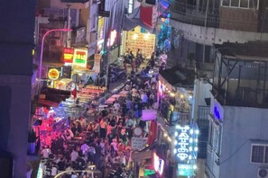 Escena de calle concurrida, con muchas personas y letreros iluminados.