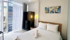 A hotel room with a bed, a desk, a wardrobe, and a view of the outside. - Atusy Boutique Hotel (Ho Chi Minh City)