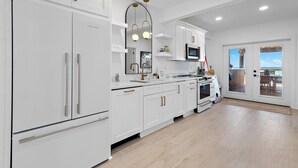 Una cocina moderna con armarios blancos, electrodomésticos de acero inoxidable y un amplio ventanal con vistas al exterior.