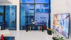 Un hall d’hôtel moderne doté d’une cloison en verre, d’un sol en marbre, d’un grand téléviseur à écran plat et d’un élément décoratif mural.