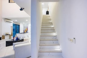 A staircase with white marble steps leading to a landing, a white wall, and a modern interior design. - Your Days PLUS pool villa (Pattaya)