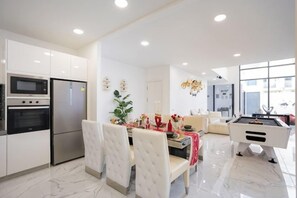 A modern kitchen with built-in appliances, a dining area with a pool table, and a large window providing natural light. - Your Days PLUS pool villa (Pattaya)