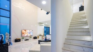 Un intérieur moderne avec un sol en marbre, un escalier, un téléviseur à écran plat et un coin salon.