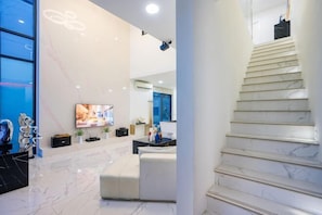 A modern interior with a marble floor, a staircase, a flat-screen TV, and a seating area. - Your Days PLUS pool villa (Pattaya)
