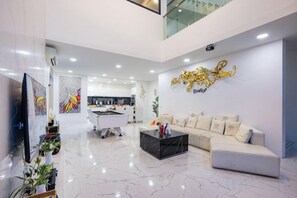 A modern living room with a sofa, a coffee table, and a flat-screen TV. - Your Days PLUS pool villa (Pattaya)