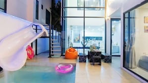 Un espace intérieur moderne doté d’un toboggan, d’un coin salon et de murs en verre qui permettent d’admirer l’intérieur.
