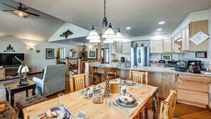 A spacious kitchen with wooden cabinets, a dining area with a wooden table and chairs, and a ceiling fan. - Hike, Fish & Unwind: Remote Escape in Montana (Saint Regis)