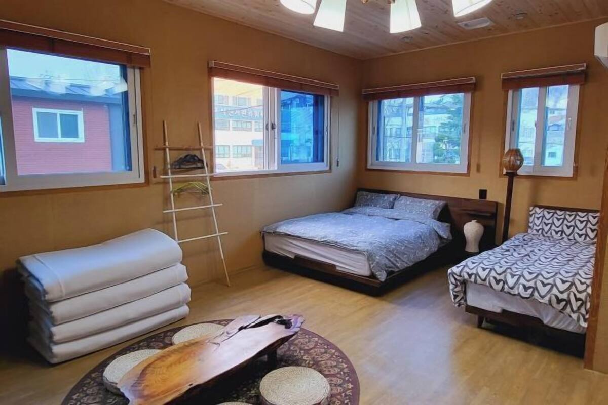 Une petite pièce agréable et chaleureuse, avec deux lits, un plafond en bois et de grandes fenêtres.