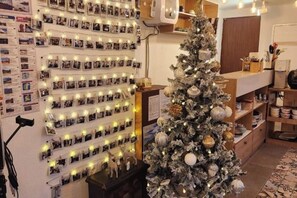 Een kamer met een fotopresentatie aan de muur, een kerstboom en een open haard.