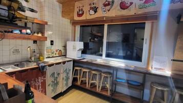 A kitchen with a refrigerator, wooden stools, and a window with a view.