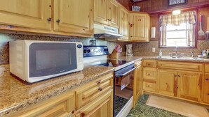 A kitchen with wooden cabinets, a microwave, stove, and a sink. - Walk to Greers Ferry Lake! Home w/ Dock Access (Greers Ferry)