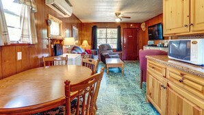 A wooden interior with a dining table, chairs, a sofa, a television, and a microwave. - Walk to Greers Ferry Lake! Home w/ Dock Access (Greers Ferry)