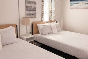 A bedroom with two beds, a nightstand with a lamp, and a motivational quote on the wall.
