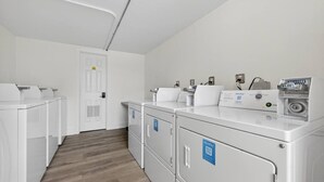 Une laverie équipée de plusieurs machines à laver et de plusieurs sèche-linge, d’un terminal de paiement et d’une porte dotée d’une serrure de sécurité.