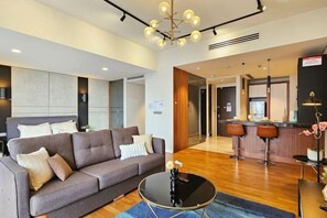 A modern hotel room with a sofa, a round coffee table, a bar area, and a kitchen in the background. - Anggun KLCC Spacious Studio Steps to Monorail & LRT FREE Parking (Kuala Lumpur)