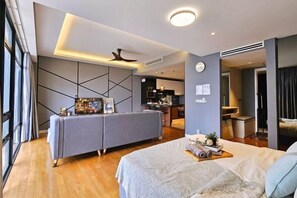 Une chambre d’hôtel moderne équipée d’un lit, d’un canapé, d’un bureau et offrant une vue sur la cuisine.