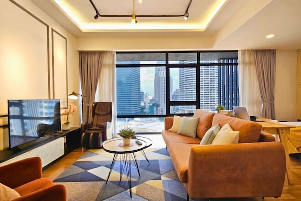 A modern living room with a sofa, armchairs, a coffee table, and a TV.