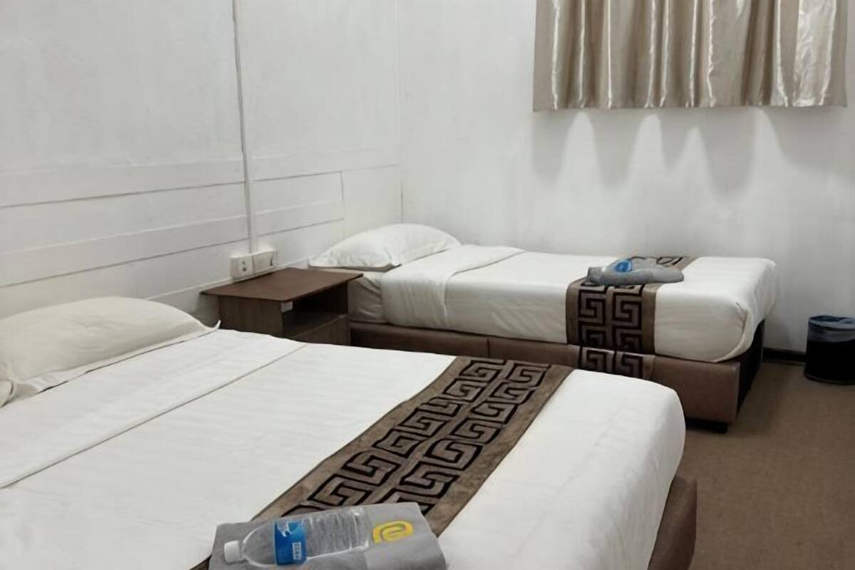 A hotel room with two beds, a nightstand, and a window with curtains.