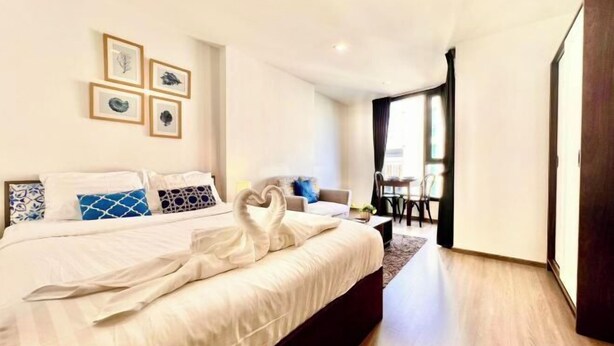 A modern hotel room with a large bed, a desk, and a view of the outdoors. - The Base Central Condominium (Phuket)