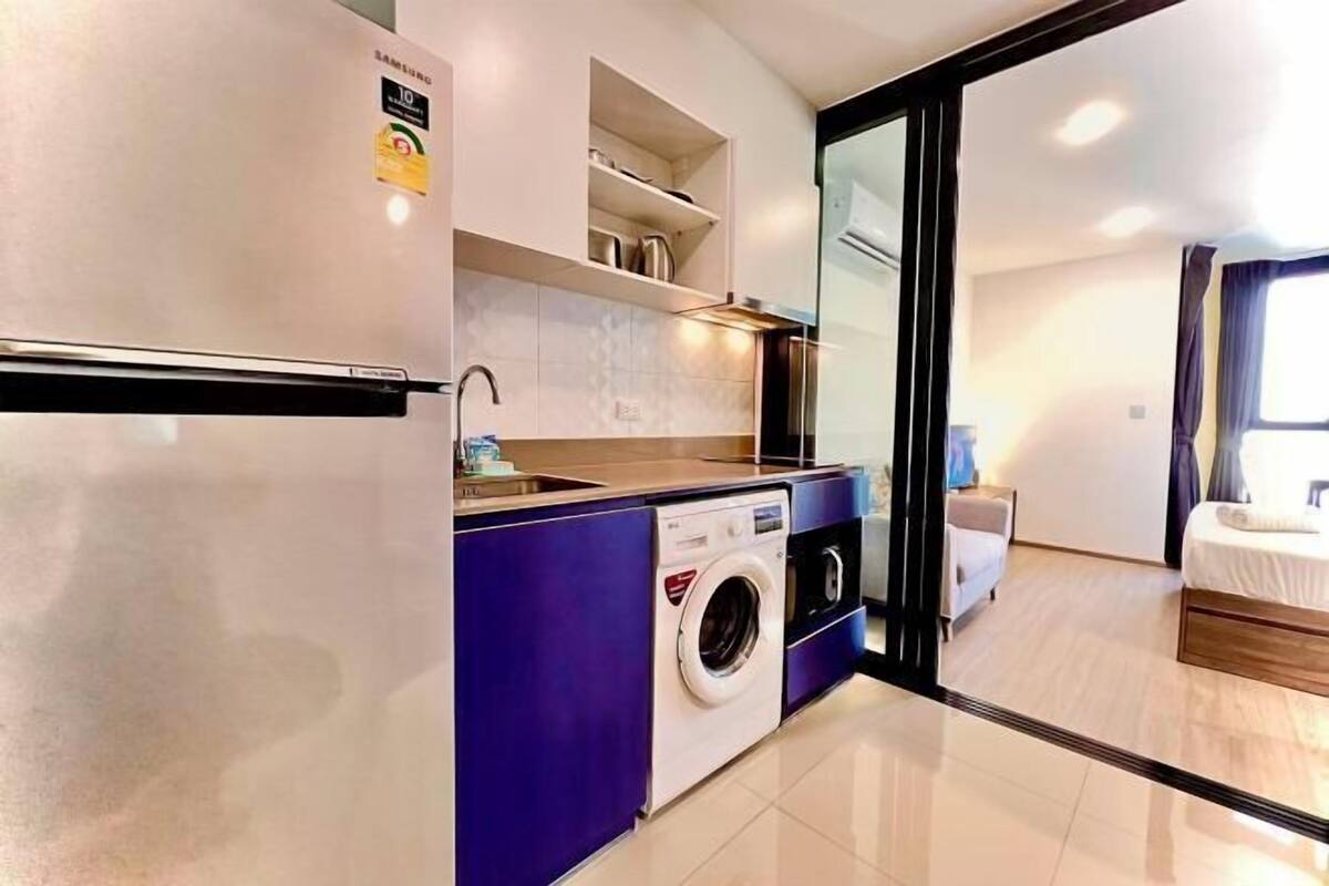 A modern kitchen with a washing machine, a refrigerator, and a built-in oven.