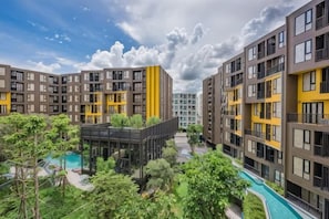 A residential building with multiple balconies, a swimming pool, and surrounding greenery. - The Base Central Condominium (Phuket)
