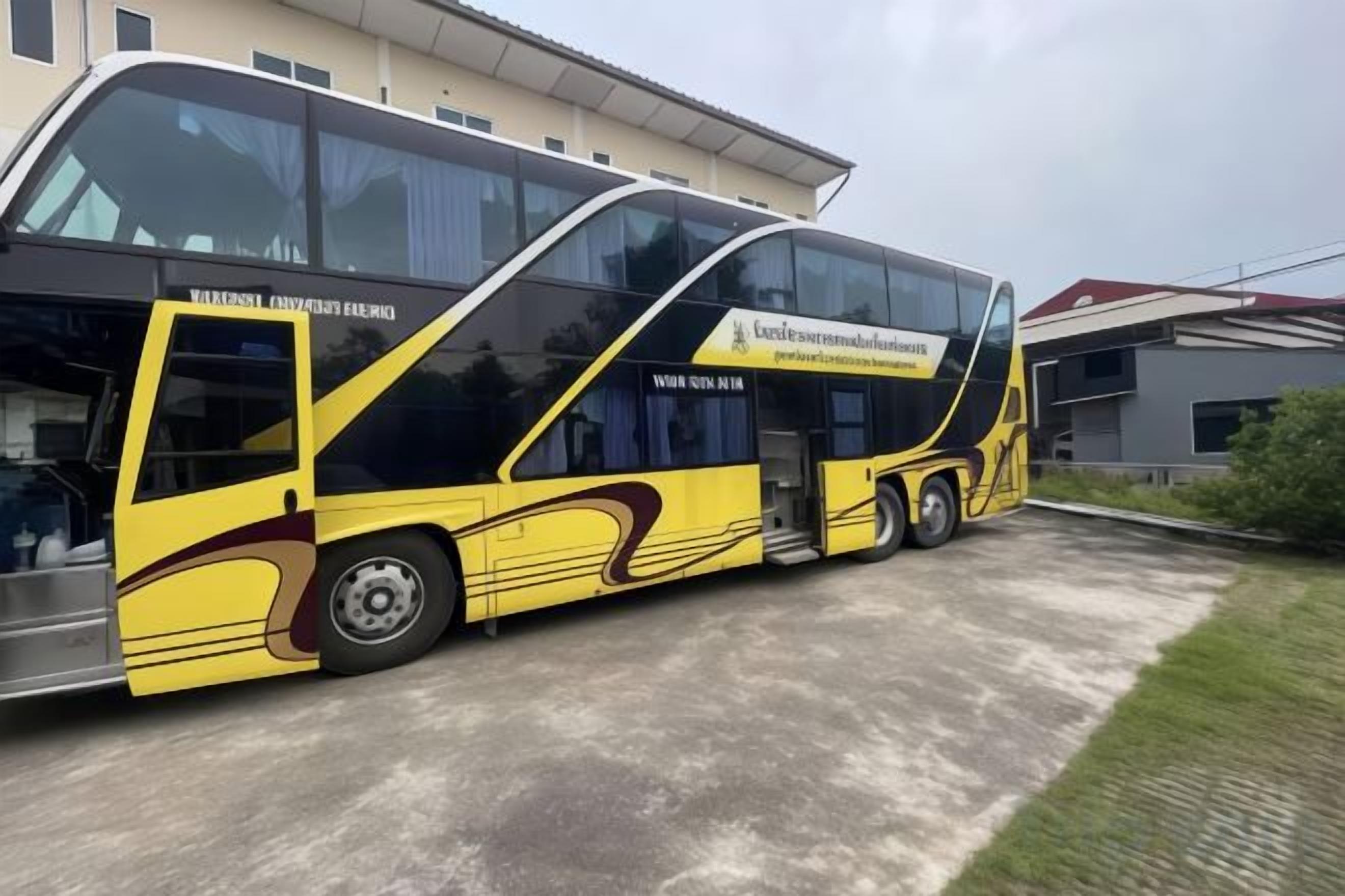Un autobús amarillo y negro estacionado frente a un edificio con un amplio ventanal.