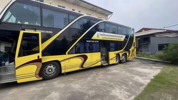 Un autobús amarillo y negro estacionado frente a un edificio con un amplio ventanal.