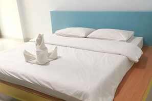 A bed with white linens and a towel sculpture on the bedspread.