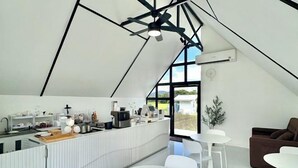 Eine moderne Küche mit einer zentralen Kochinsel, weißen Möbeln und einem großen Fenster mit Blick ins Freie.