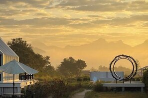 A residential area with a house, a circular outdoor structure, and a mountain range in the background. - Paradise Resort & Cafe (Chiang Dao)