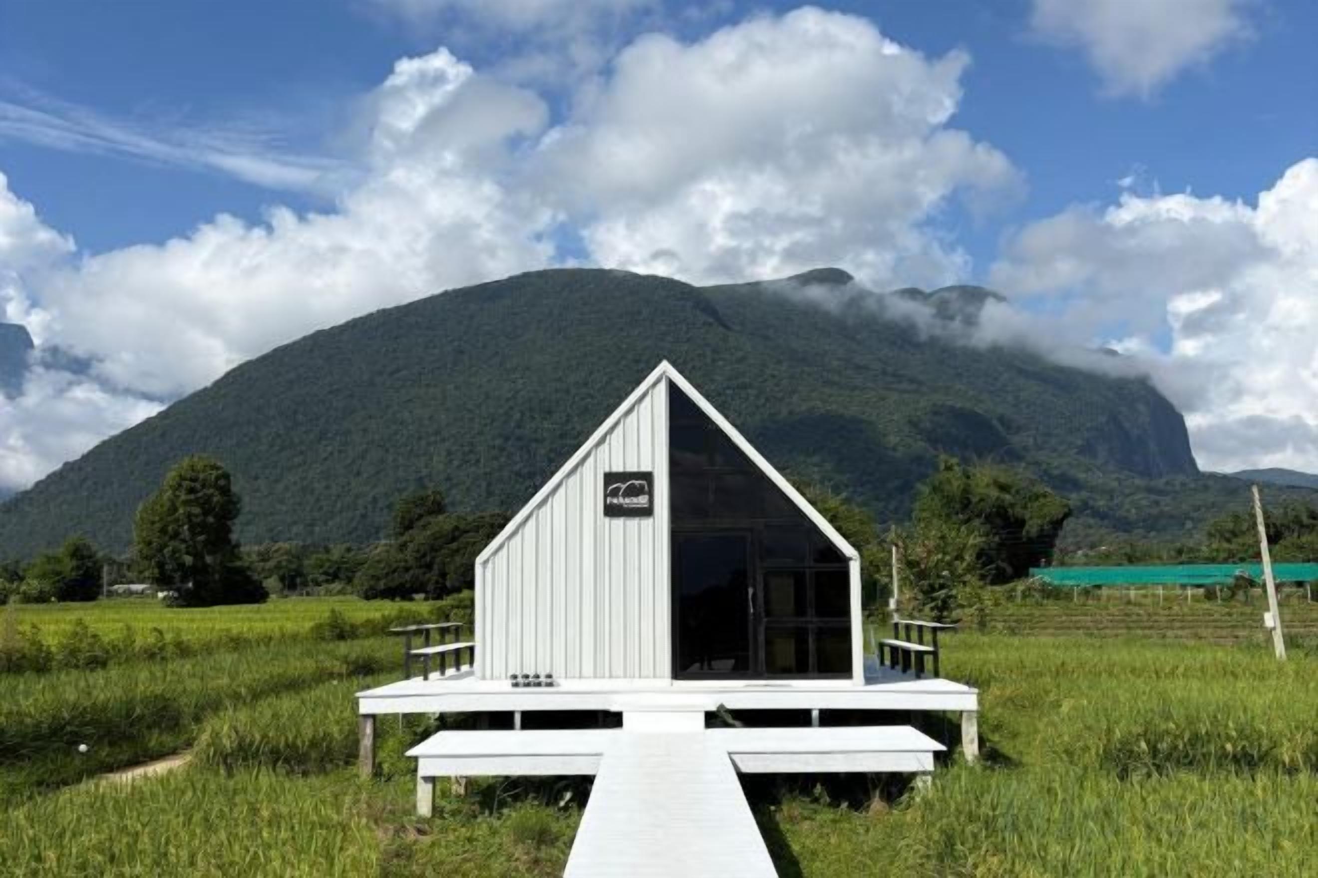 A white building with a triangular roof, a wooden deck, and a sign indicating a restaurant.