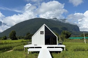 A white building with a triangular roof, a wooden deck, and a sign indicating a restaurant. - Paradise Resort & Cafe (Chiang Dao)