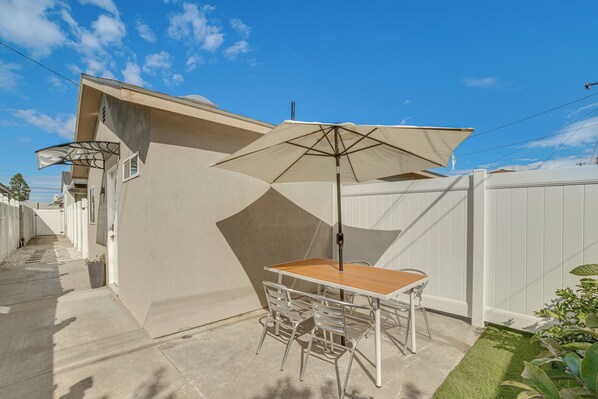 A patio with a table and chairs, an umbrella, and a white fence.