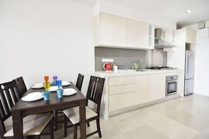 A modern kitchen with white cabinets, a built-in oven, and a dining area with a wooden table and chairs.