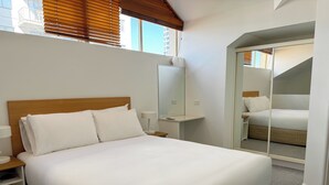 Ein Hotelzimmer mit einem großen Bett, einem Nachttisch, einem Spiegel und Blick auf den Balkon.