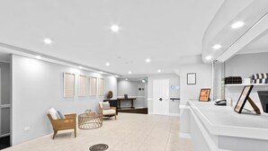 Ein moderner Empfangsbereich mit Empfangstresen, einer Sitzecke inklusive Sofa und Sesseln sowie gerahmten Kunstwerken an den Wänden.