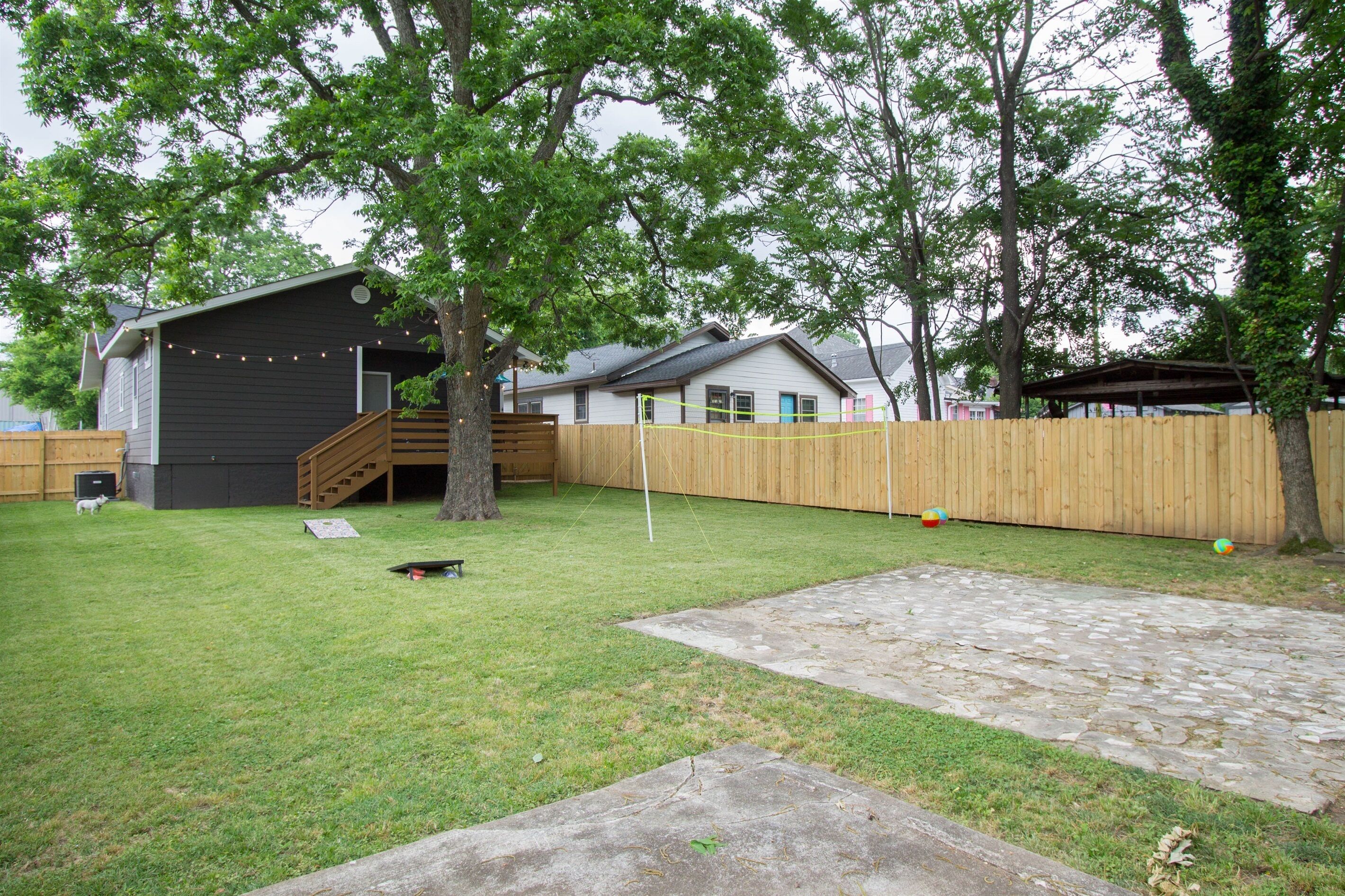 Ein Garten mit Holzzaun, Trampolin und einem Haus mit dunkler Fassade.