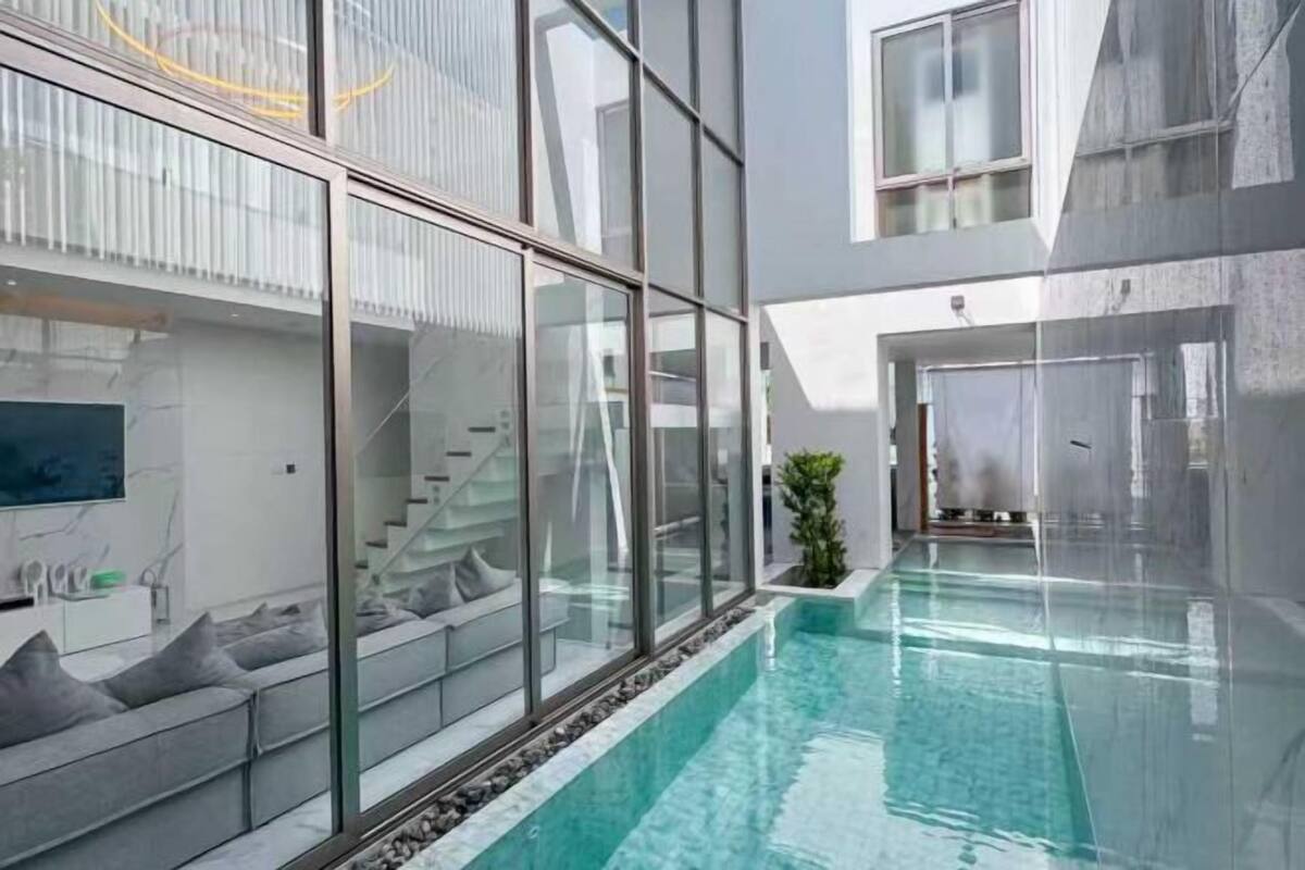 Un bâtiment moderne doté d’une façade en verre, d’une piscine et d’un escalier menant à un niveau supérieur.
