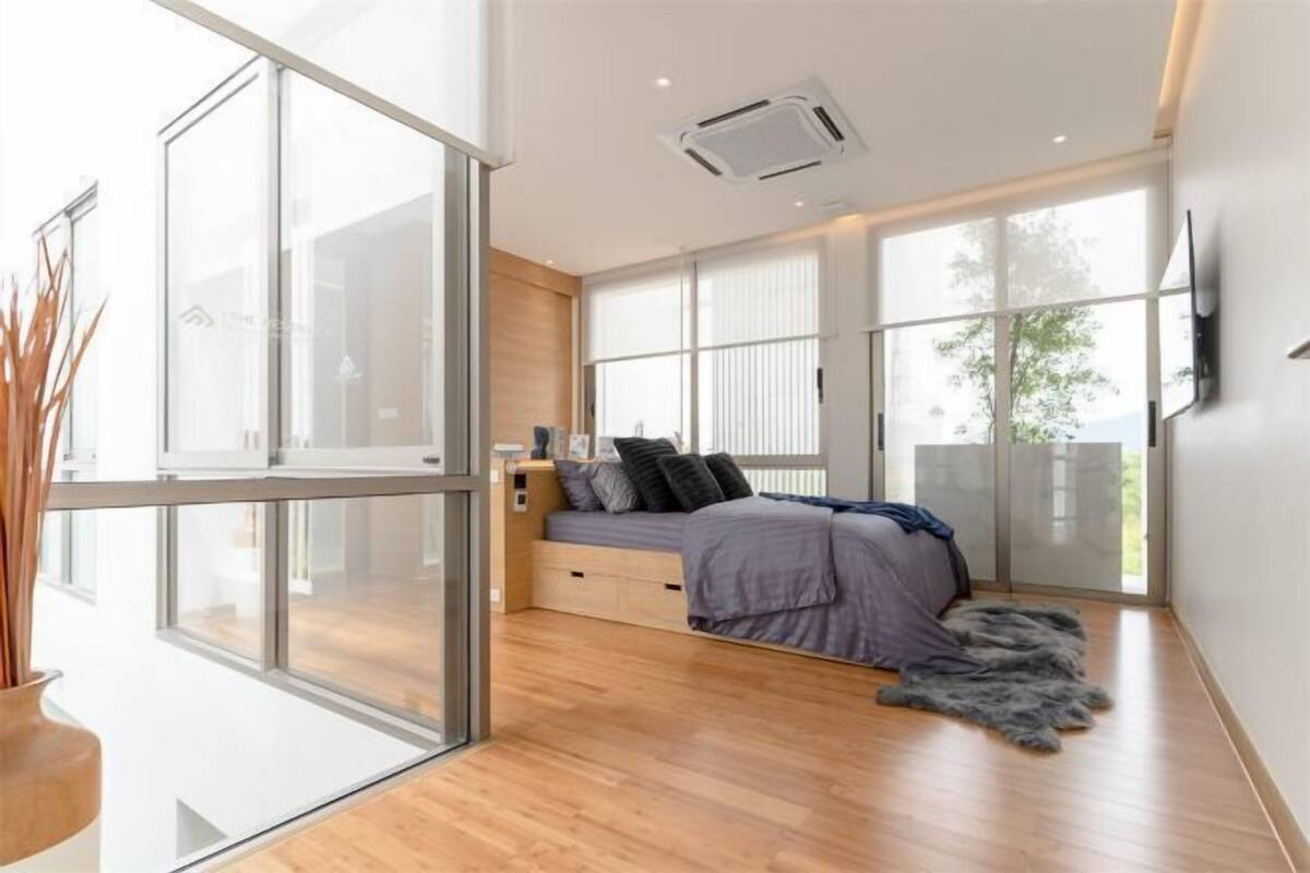 Une chambre moderne avec un lit, une télévision et une grande fenêtre.