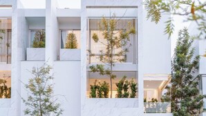 Un edificio moderno con varios balcones, ventanas amplias y plantas de interior.